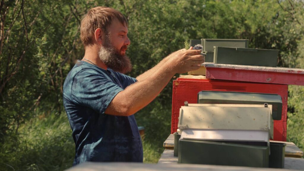 A man working outdoors with a beehive